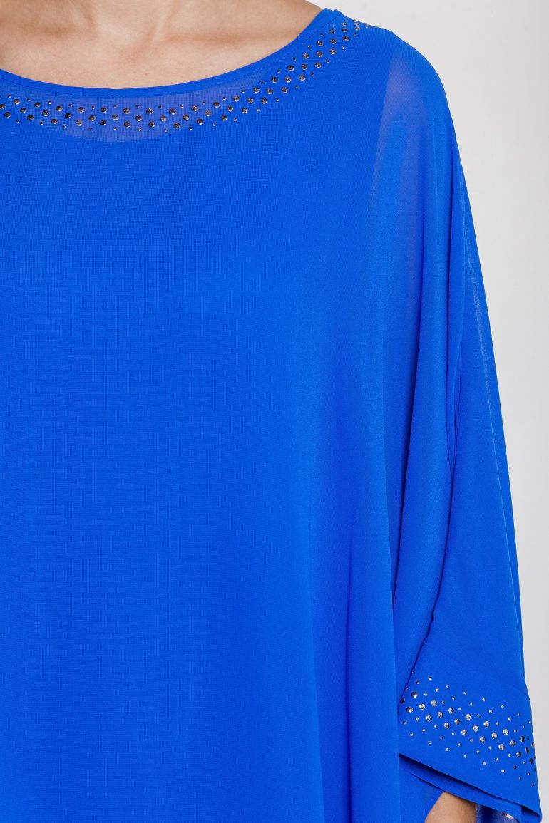 Modelka prezentuje kobaltową sukienkę z szyfonu marki Vito Vergelis. Rękaw z ozdobną naklejką.
