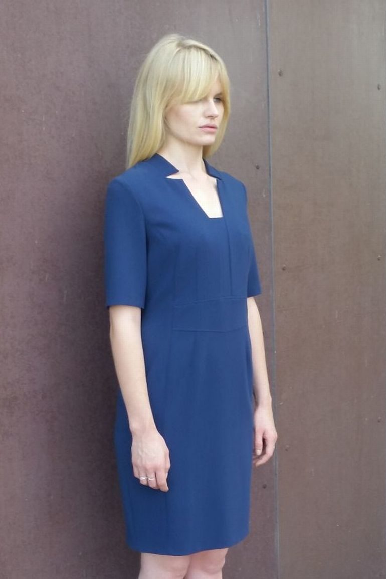 Modelka w sukience Vito Vergelis. Niebieska sukienka biznesowa z cięciami.